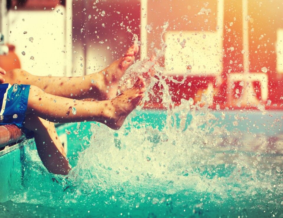 ragazzo che schizza l'acqua con i piedi in piscina