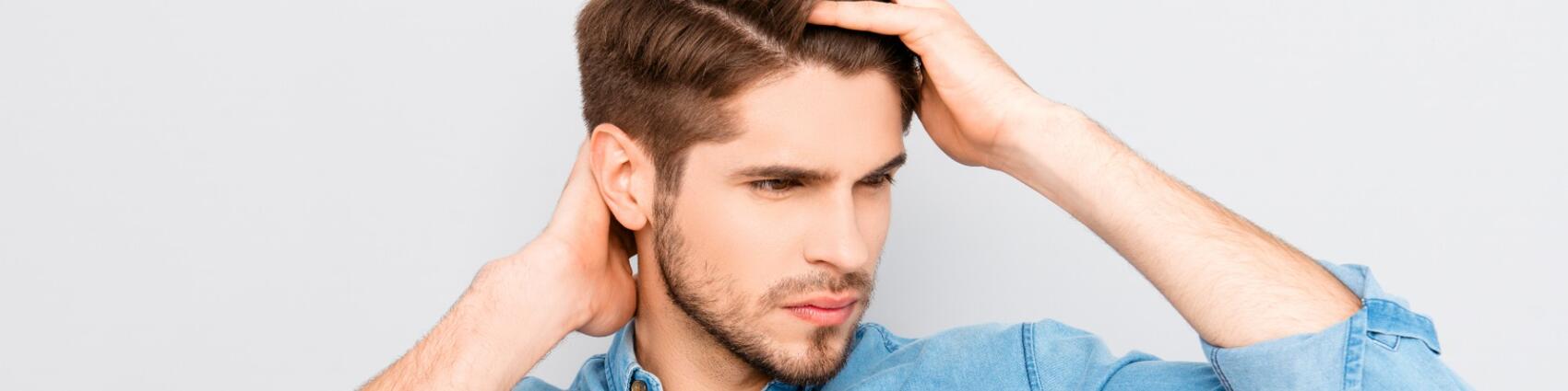 Man running hand through thick hair after successful hair transplantation surgery.