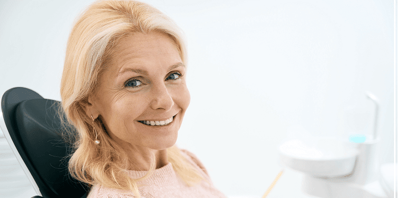 Old lady sitting in a dentist chair smiling