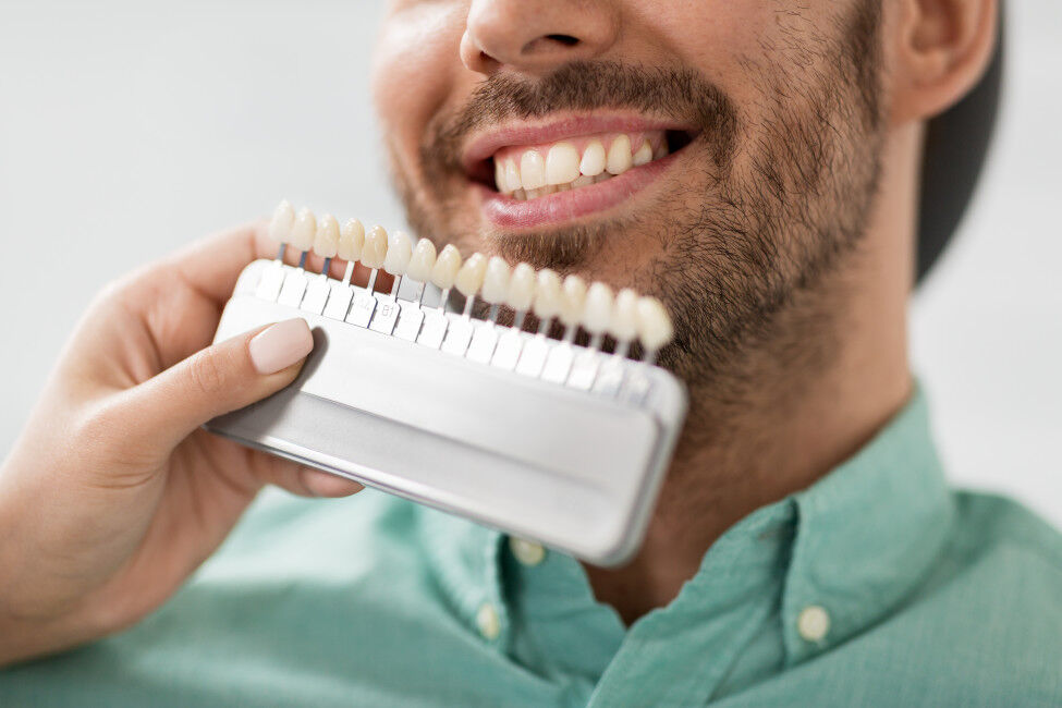 Mann lächelt und wartet auf die Anpassung seiner Veneers.