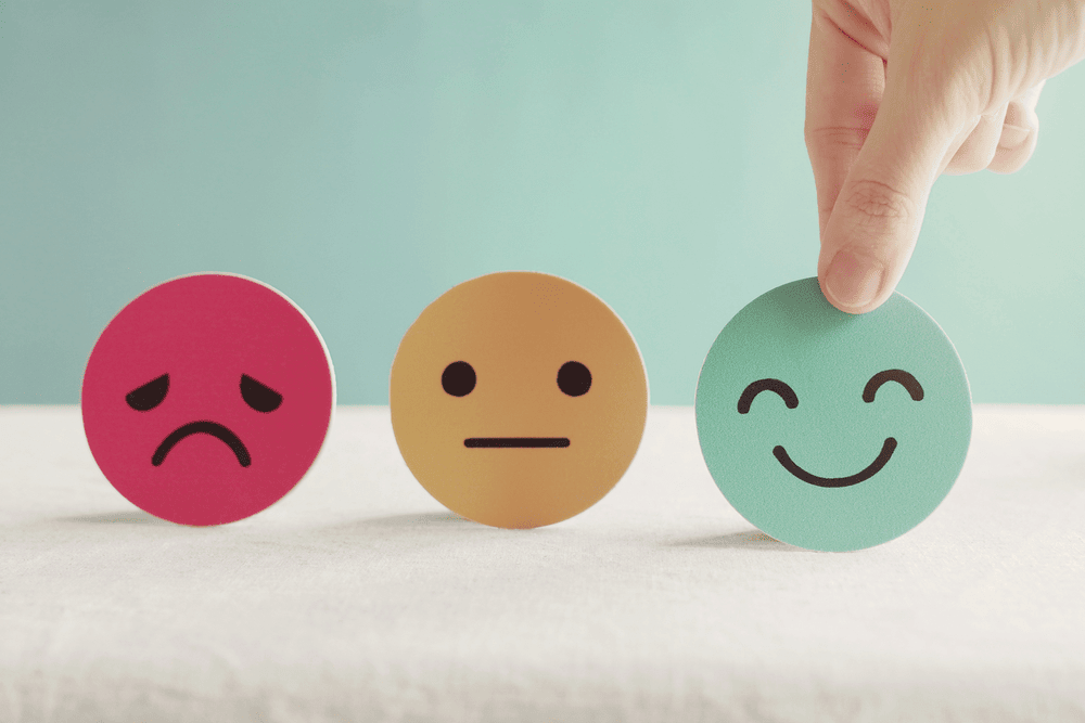 Picture of a person picking a happy face out of neutral and sad face