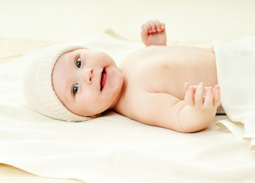 Happy baby lying on back smiling.