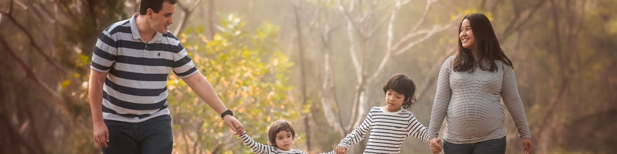 Happy family walking in the woods holding hands after successful IVF.