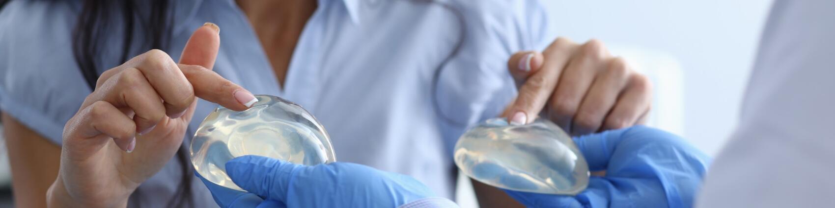 Smiling woman choosing breast implants from a doctor.