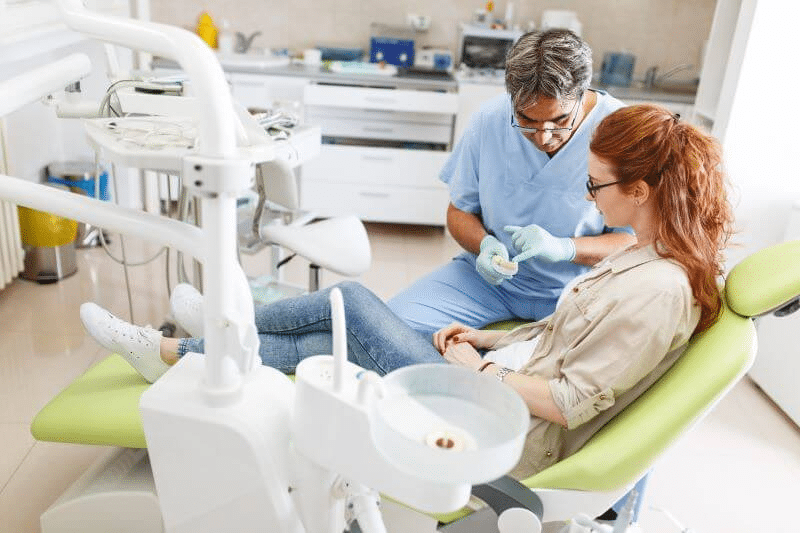 Ein Zahnarzt klärt ein Patientin über die Haltbarkeit von Veneers vs Kronen auf.