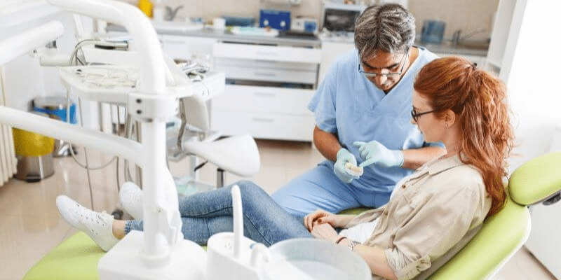 A dentist explains the durability of veneers vs crowns to a patient.