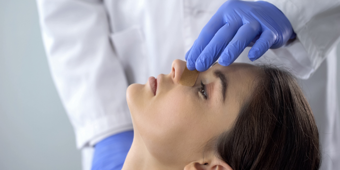 Arzt sieht sich die Nase einer jungen Frau nach der Rhinoplastik an