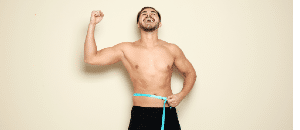 Happy man measuring waist after weight loss surgery.