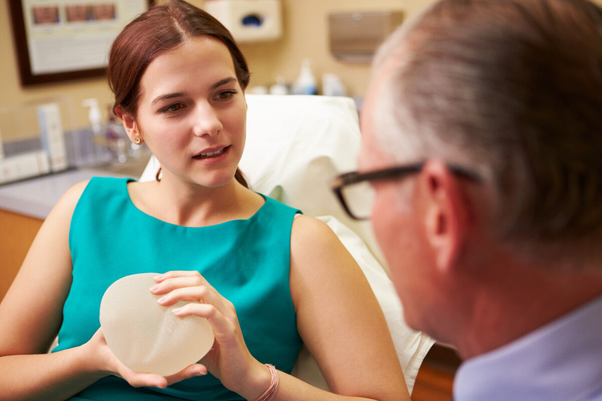 Patientin hält Implantat während sie mit Arzt spricht
