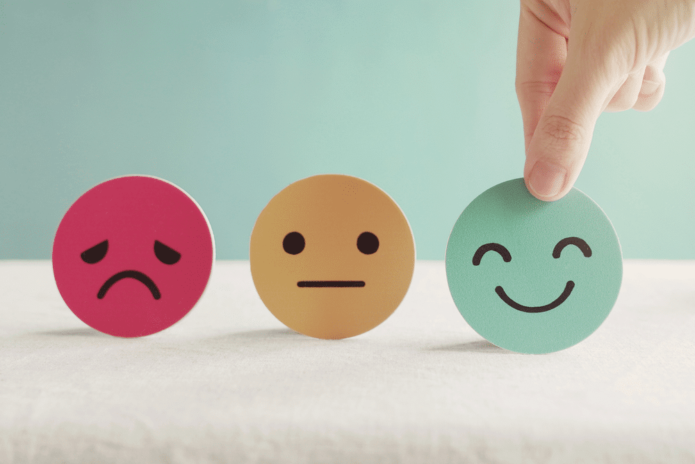 Picture of a person picking a happy face out of neutral and sad face
